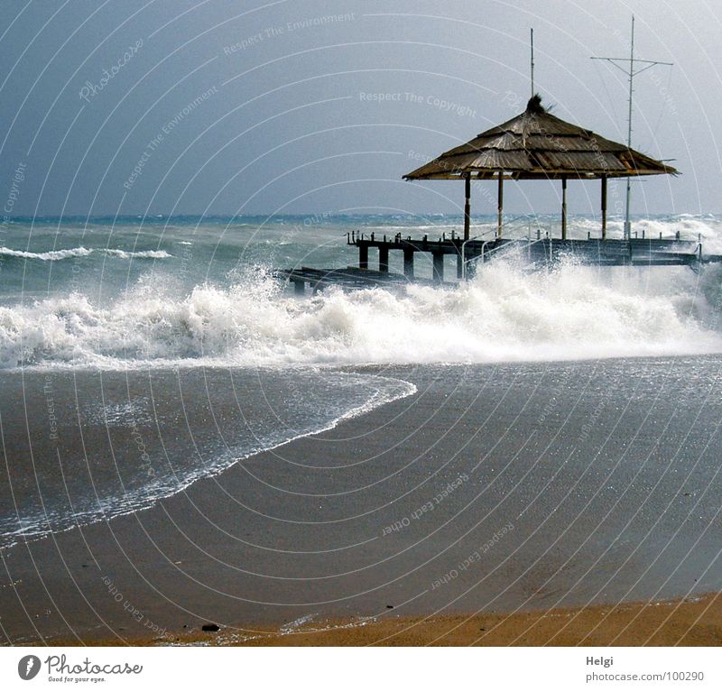 Steg mit Sonnenschutzdach am Strand bei stürmischer See Meer Wellen Gischt Schaum nass schäumen fließen Dach Sturm Türkei Brandung weiß braun laufen