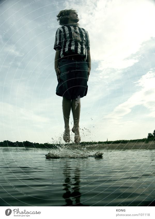 wassergeburt springen Strand Trikot Wellen Wasseroberfläche Wolken Junger Mann Freude Spielen spritzen Wassertropfen in die luft gehen fliegen hoch aufwärts