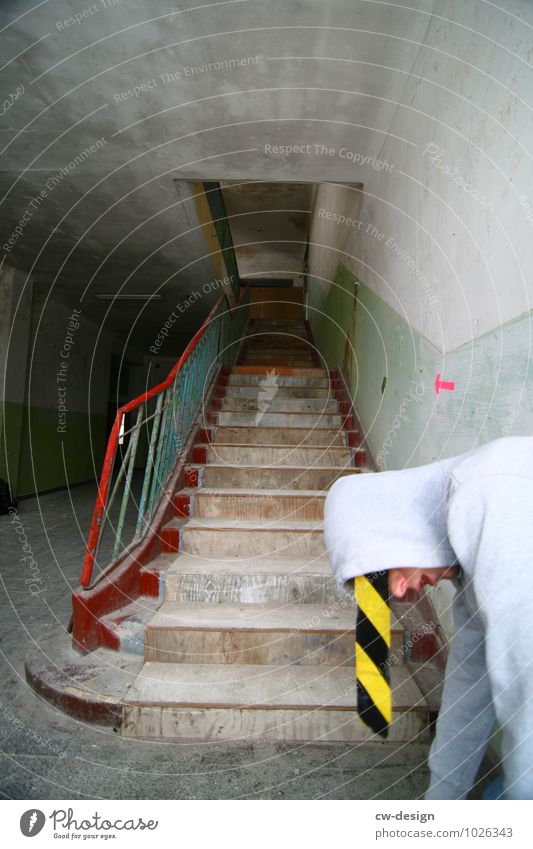 Jugendlicher posiert mit Absperrband aus der Kapuze hängend jung gelb schwarz grau trist Treppe Junger Mann Absperrung gestreift Streifen Farbfoto Baustelle