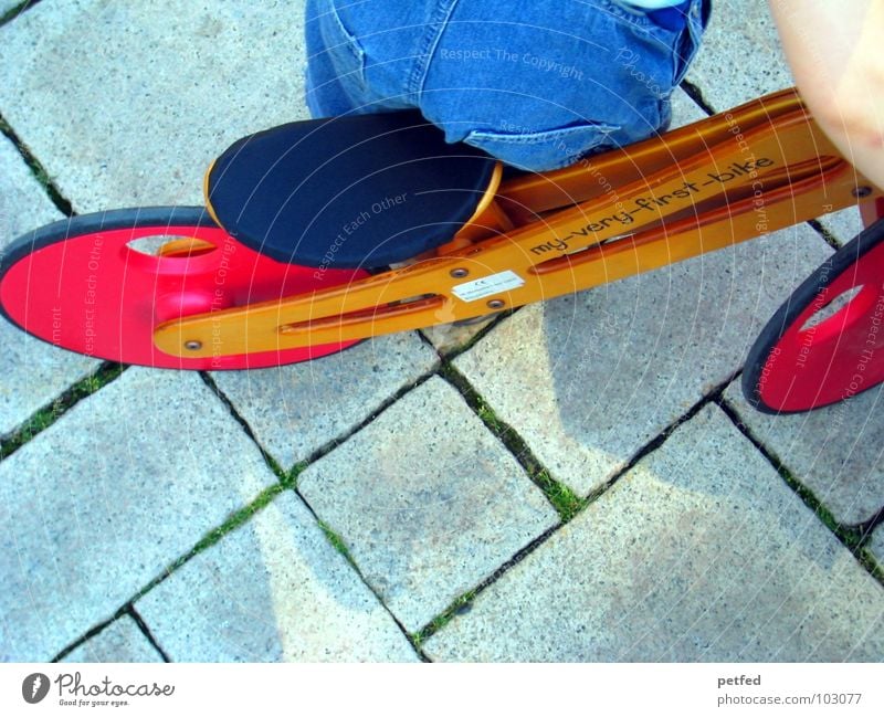 MY-VERY-FIRST-BIKE Kind klein Fahrrad Spielzeug Spielen rot stehen fahren Geschwindigkeit langsam rechts Hose braun Kleinkind Mensch Freude blau Jeanshose Arme