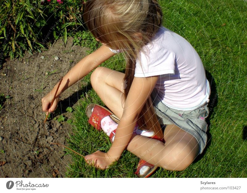 In Kreativität vertieft Mädchen Stock Kind Sommer langhaarig blond schreiben Sand Rasen zeichnen Zweig sitzen