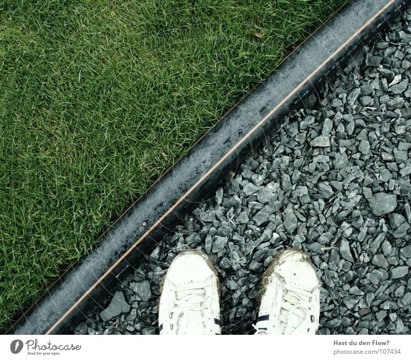 wo steh ich? Gras Kieselsteine Schlauch Grenze grün weiß schwarz Grenzübergang Neue Welt diagonal Trennlinie Industrie graß Stein white black Fuß Übergang Natur