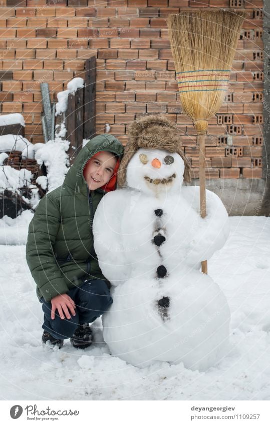 Schneemann und Kind im Hof Freude Glück Spielen Ferien & Urlaub & Reisen Winter Junge Frau Erwachsene Kindheit Natur Gebäude Hut Lächeln Fröhlichkeit weiß