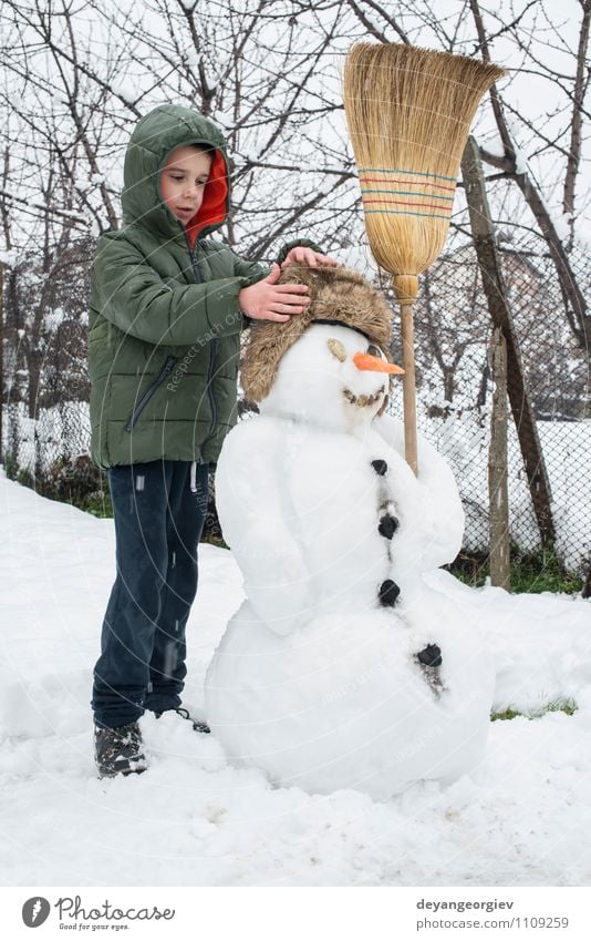 Schneemann und Kind im Hof Freude Glück Spielen Ferien & Urlaub & Reisen Winter Junge Frau Erwachsene Kindheit Natur Gebäude Hut Lächeln Fröhlichkeit weiß