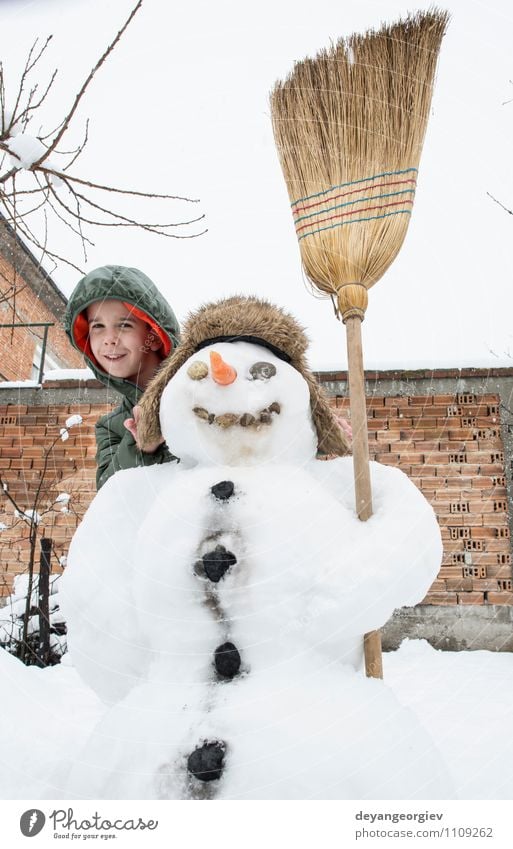 Schneemann und Kind im Hof Freude Glück Spielen Ferien & Urlaub & Reisen Winter Junge Frau Erwachsene Kindheit Natur Gebäude Hut Lächeln Fröhlichkeit weiß