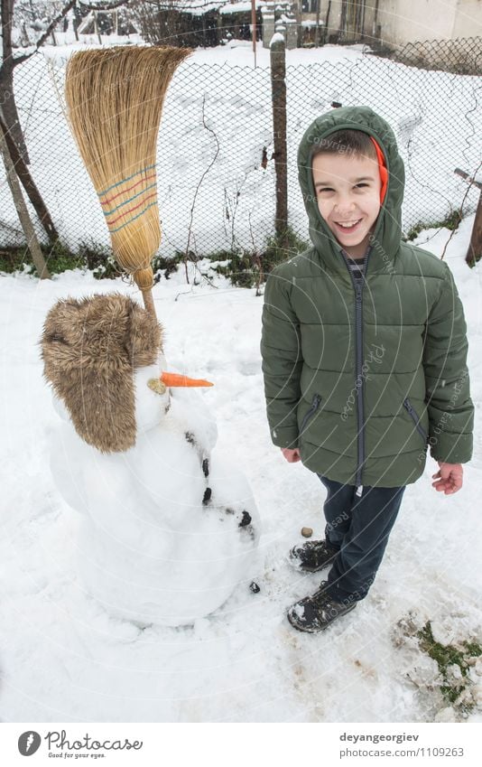 Schneemann und Kind im Hof Freude Glück Spielen Ferien & Urlaub & Reisen Winter Junge Frau Erwachsene Kindheit Natur Gebäude Hut Lächeln Fröhlichkeit weiß