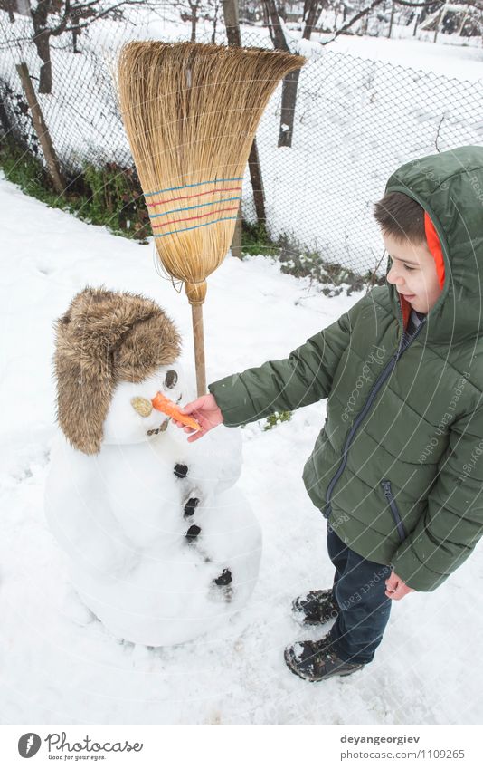 Schneemann und Kind im Hof Freude Glück Spielen Ferien & Urlaub & Reisen Winter Junge Frau Erwachsene Kindheit Natur Gebäude Hut Lächeln Fröhlichkeit weiß