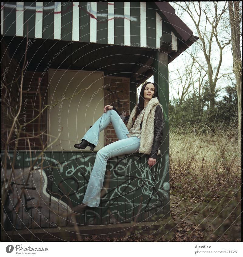 lässig Ausflug Junge Frau Jugendliche 18-30 Jahre Erwachsene Landschaft Schönes Wetter Baum Gras Sträucher Park Hütte Jeanshose Jacke Fell Stiefel schwarzhaarig