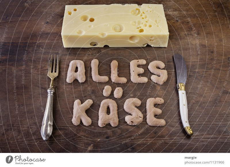 Die Buchstaben ALLES KÄSE auf einem rustikalen Holzbrett mit einem Stück Loch - Käse und Messer und Gabel Frühstück Abendessen Picknick Bioprodukte Diät Fasten