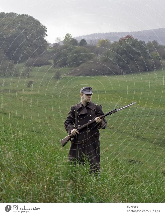 Heimatfront. Gewehr Uniform Wiese Baum Baseballmütze Mantel Bayonett Wolken grau Krieg Rucksack Wald Mann Armee Soldat kämpfen obskur Weide Natur Kappe War