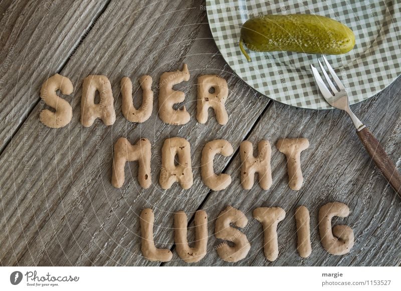 Die Buchstaben SAUER MACHT LUSTIG neben einem Teller mit einer sauren Gurke und einer Gabel Lebensmittel Gemüse Ernährung Frühstück Abendessen Büffet Brunch