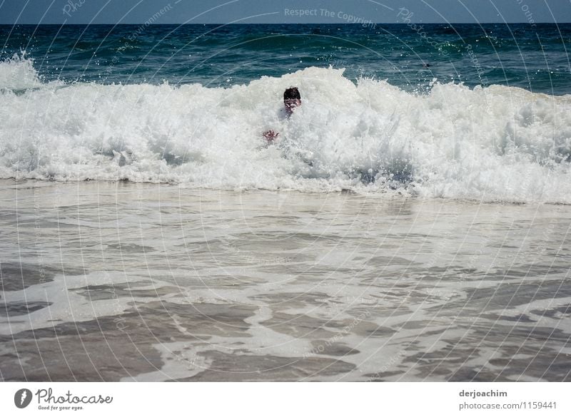 Schaumbad im Meer bei starken Brandungswellen . Man sieht einen Kopf aus den Wellenkamm  heraus schauen. Freude sportlich Schwimmen & Baden Im Wasser treiben