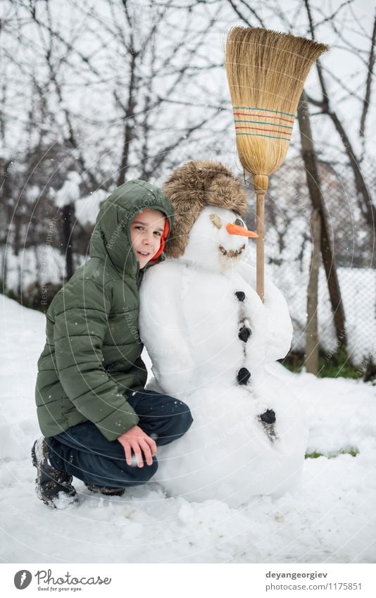 Schneemann und Kind im Hof Freude Glück Spielen Ferien & Urlaub & Reisen Winter Junge Frau Erwachsene Kindheit Natur Gebäude Hut Lächeln Fröhlichkeit weiß