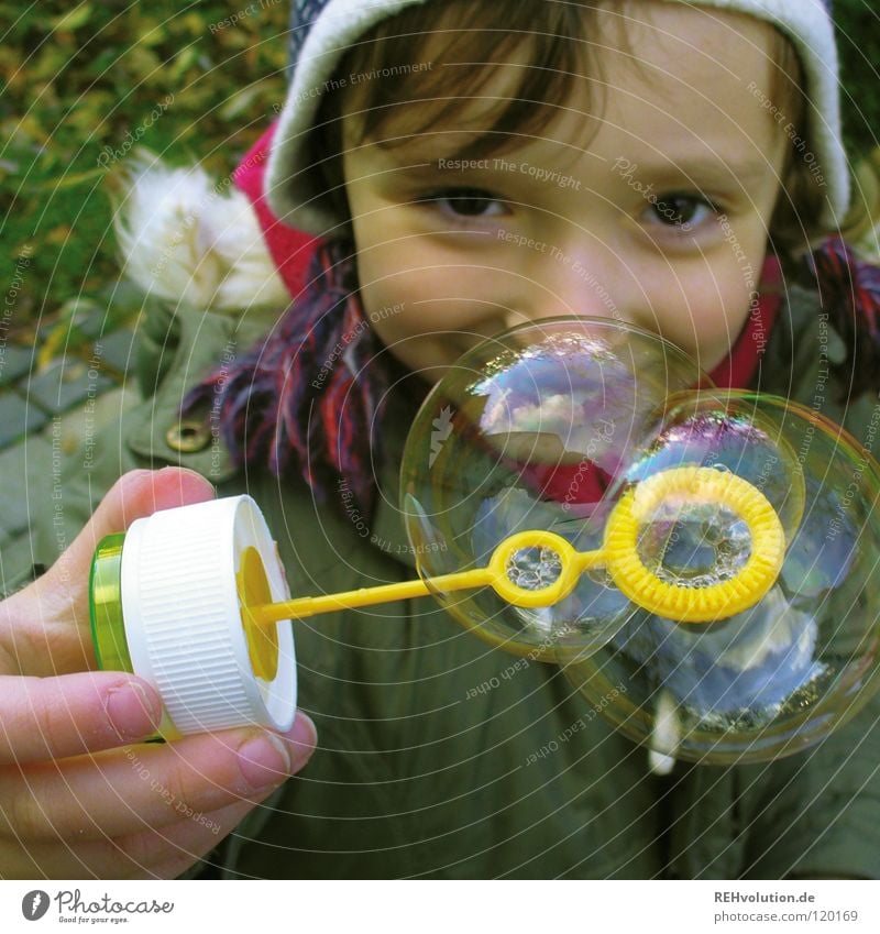 Guck ma! Kind Spielen Kleinkind Kindergarten Seifenblase Verschmitzt Junge kalt Winter grün Mütze blasen klein süß Freude Blick Beleuchtung Auge Garten Soap