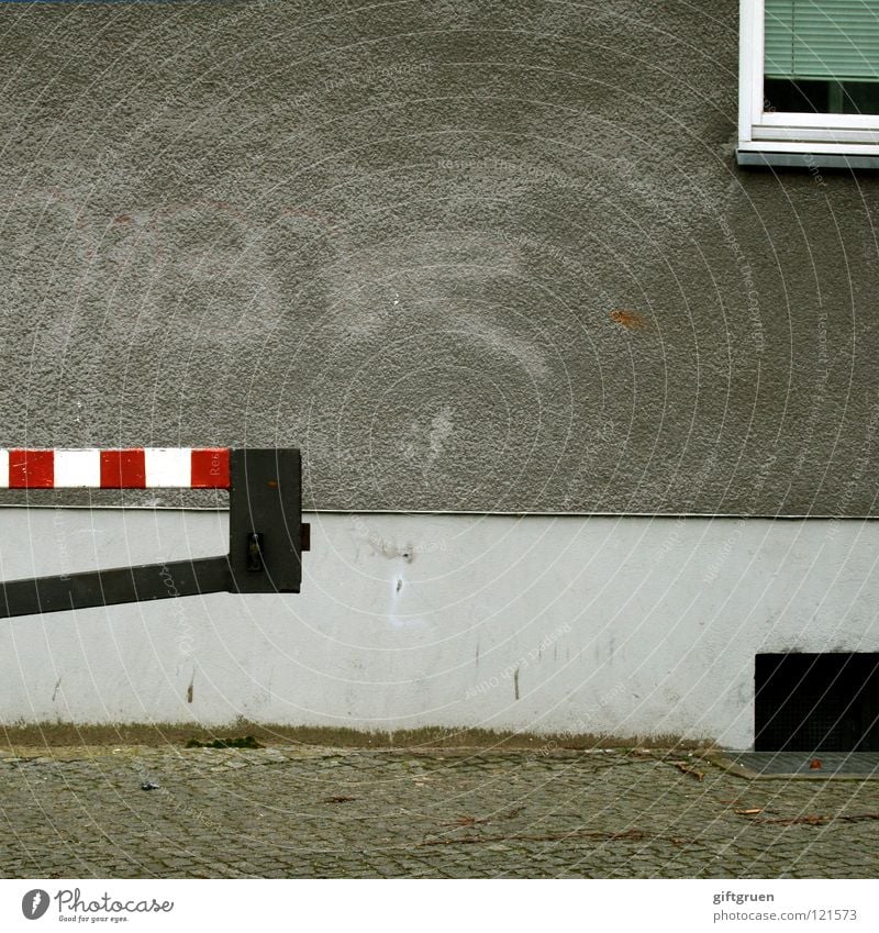 pommes rot-weiß Schranke Fassade Haus Fenster Jalousie trist grau gestreift Kellerfenster Detailaufnahme Verkehr grauzone Straße