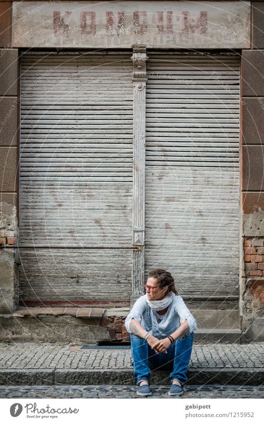 Junge Frau sitzt auf dem Gehweg vor einem verlassenen Haus Mensch feminin Erwachsene Leben 1 Subkultur Dorf Kleinstadt Altstadt Fassade Verkehrswege Straße