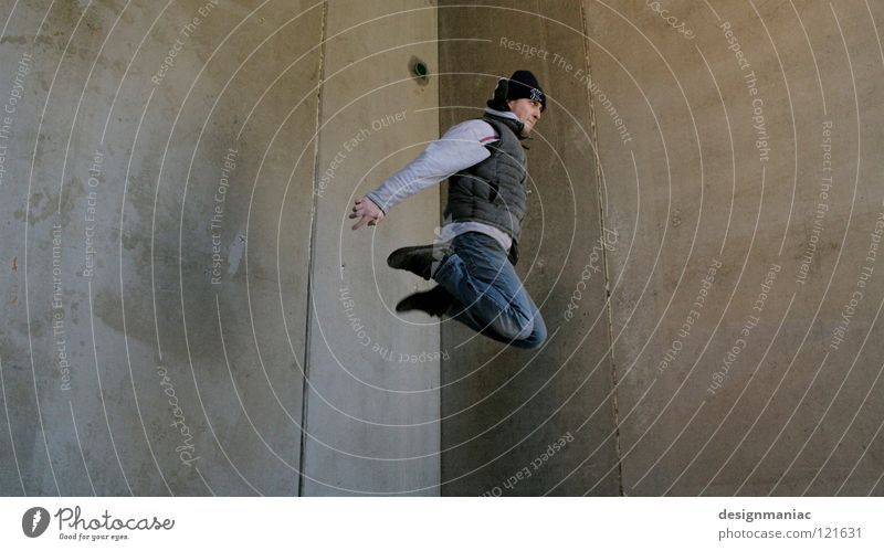 Urban Freestyle Le Parkour Beton Wand Mann Mütze grau Abfluss springen Schweben Winter kalt dreckig Weste Knie leer Schwerelosigkeit Ghetto Froschperspektive