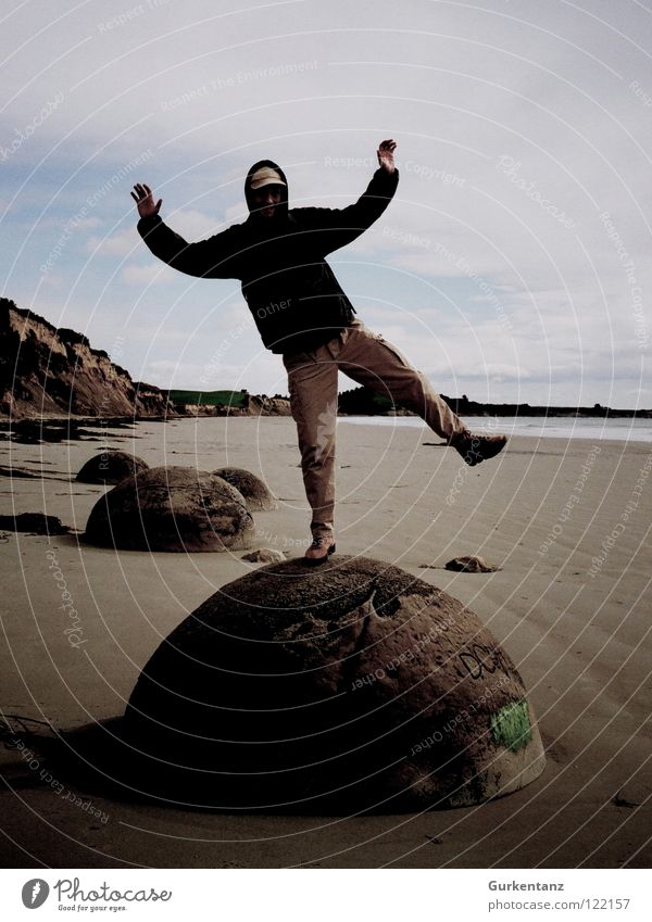 Giant man on the moon Neuseeland Moeraki Moeraki Boulder Strand Südinsel Mann Herbst Regenjacke Kapuze Baseballmütze Körperhaltung Küste Meer Stein Mineralien