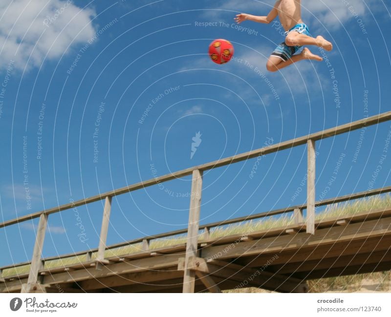 engelsfußball Sylt Strand Steg Hose schießen Spielen springen Luft Schweben kopflos Wolken Froschperspektive rot Freude Funsport Ball fallen Bewegung Sand Arme