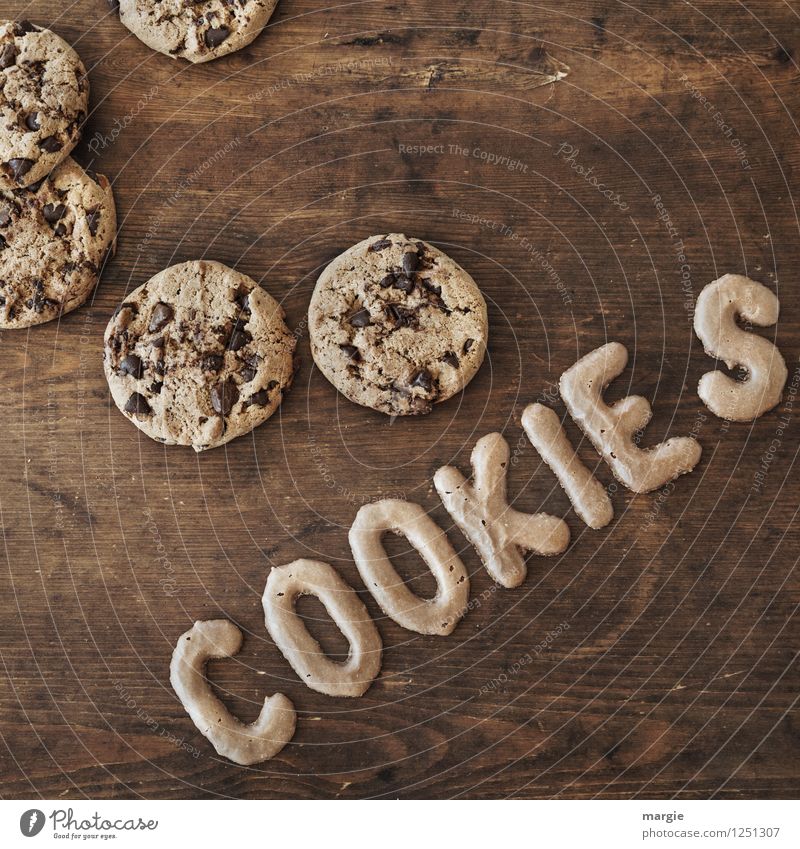 Auf einem rustikalen Holztisch mehrere Plätzchen und die Buchstaben COOKIES Lebensmittel Getreide Teigwaren Backwaren Kuchen Dessert Süßwaren Schokolade