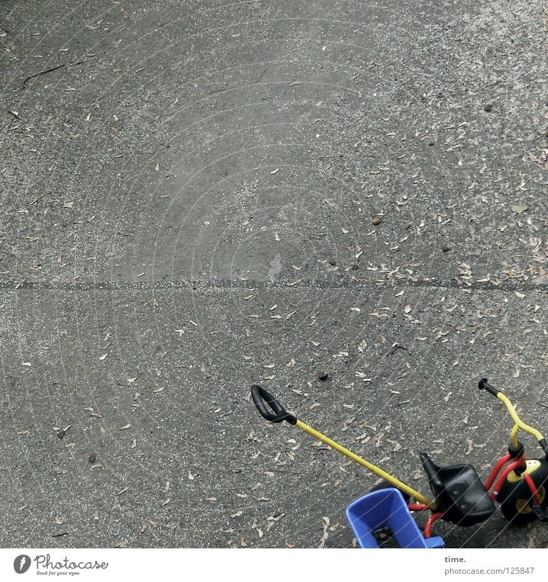 Lukas kommt gleich wieder Beton Bodenbelag Spielplatz Kinderfahrrad Spielzeug rot gelb Parkplatz Blatt Herbst Verkehr Innenhof blau Sitzgelegenheit