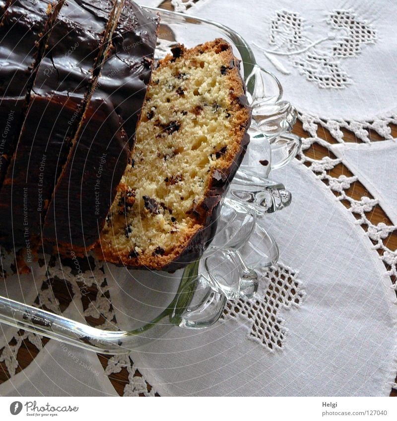 leckerer Kuchen mit Schokoladenguss auf einer Glasplatte und einem Tisch mit einer weißen, spitzenverzierten Tischdecke Sonntag Nachmittag süß Glasscheibe