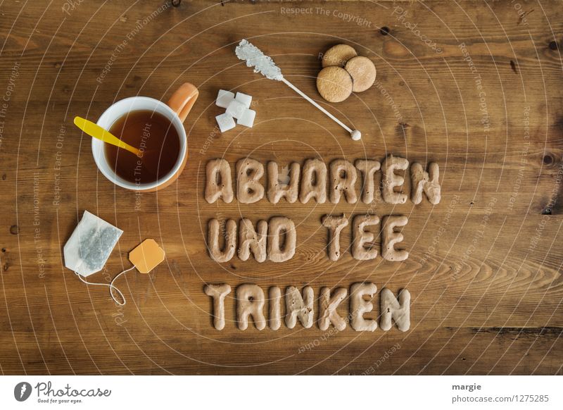 ABWARTEN UND TEE TRINKEN: eine Teetasse mit Teebeutel, Zucker und Plätzchen auf einem Holztisch Lebensmittel Dessert Süßwaren Getränk Heißgetränk Tasse Löffel