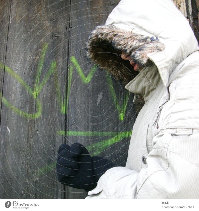 KMsto.E Kerl Körperhaltung Holz Eingang Wand Muster Holzbrett Aufschrift Schmiererei Kilometer Richtung Mütze Jacke grau Handschuhe schwarz Osten historisch