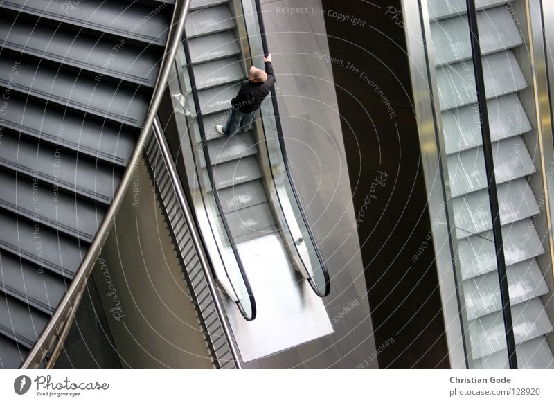 Concrete Jungle Rolltreppe gehen bequem Fußtritt Wendeltreppe Mann maskulin grau braun weiß schwarz festhalten kalt Eisen Entscheidung Einkaufspassage Arkaden