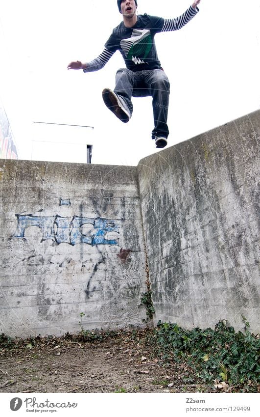 abwärts springen Mauer Sträucher Jugendkultur Wand Beton Mann maskulin lässig Graffiti Wandmalereien Mensch Erde dreckig Jugendliche Niveau Jeanshose sportlich