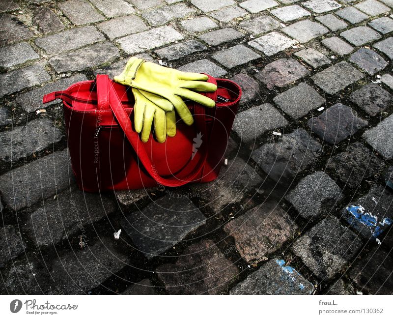 abgestellt Tasche Handschuhe rot grün Leder Platz stehen Körperhaltung Dinge Bekleidung Verkehrswege Kopfsteinplaster Straße liegen warten Ledertasche