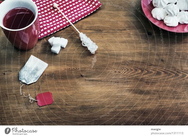 Roter Tee mit Zucker und Plätzchen auf einem Holztisch Kuchen Dessert Süßwaren Teebeutel Backwaren Getränk Heißgetränk Teller Tasse Serviette Lifestyle