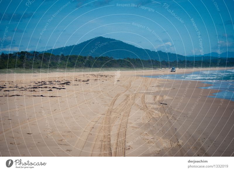 Endloser Strand von Rainbow Beach. Links gehen am Strand. Ein Auto kommt entgegen. Im Hintergrund ein mittel hoher Berg. Leben Ausflug Sommer Landschaft