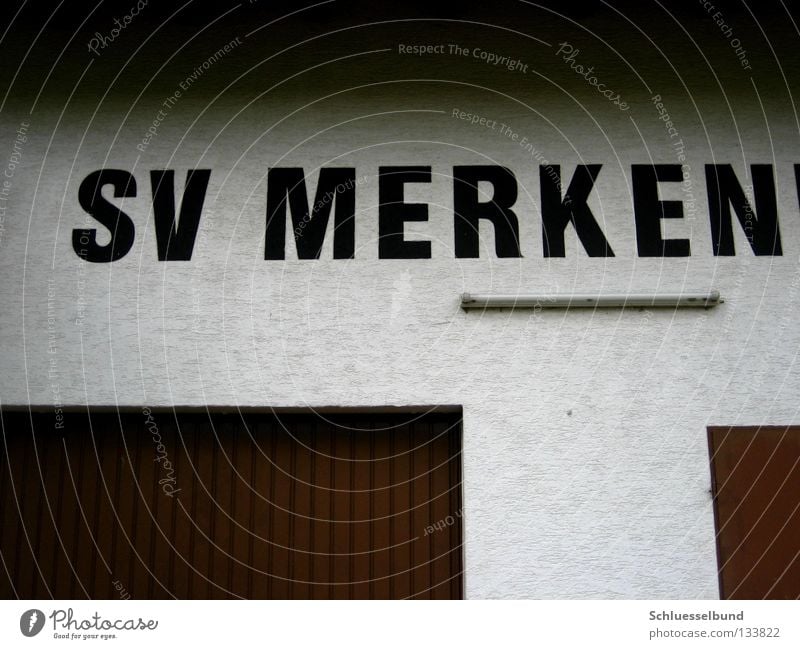 Sportverein Lampe Schriftzeichen dunkel hell braun weiß Buchstaben Wand Putz Neonlampe ansammeln Garage Garagentor Metalltür schwarz Farbfoto Außenaufnahme Tag