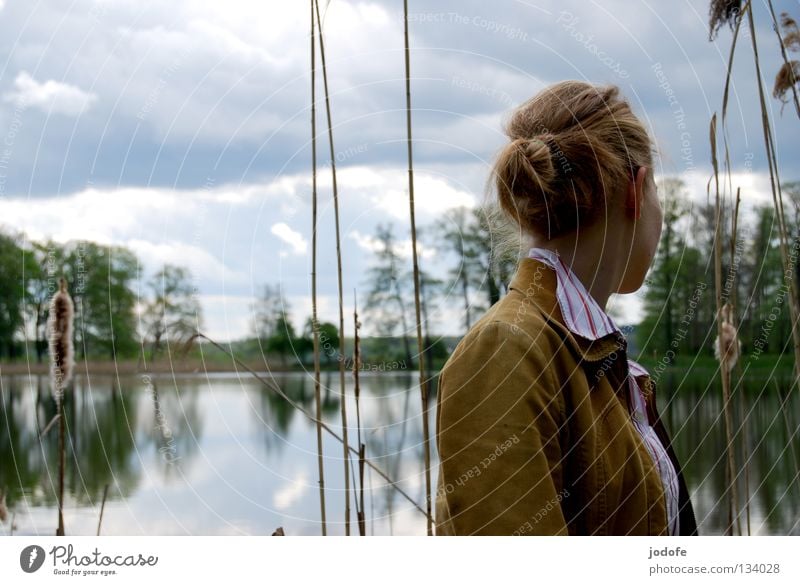 abneigung See Frau feminin Jugendliche Spiegel Baum Sträucher Park Binnensee Schilfrohr Wolken trüb Physik Frühling grün Bluse Hemd Dutt Pferdeschwanz Zopf