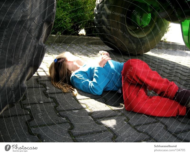 Schön Sonnig Sträucher Verkehrswege Hose Pullover Schuhe Stein grün schwarz Sonnenlicht Parkplatz parken liegen träumen Kind Mädchen langhaarig Reifen Rad