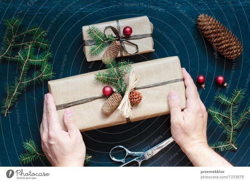 Eingewickelte Weihnachtsgeschenke auf dem Tisch Schere Hand Papier Verpackung Kasten Schnur Kultur Tradition Gast Dezember Geschenk heimwärts horizontal Kiefer