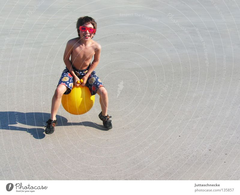 Häschen hüpf Kind Junge Spielen Spielzeug hüpfen springen Känguruh gelb Brille Sonnenbrille retro Sommer Freude Hüpfball Känguruhball lustig Schatten hoch