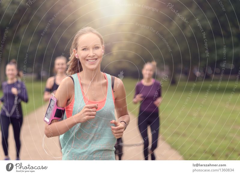 Athletische hübsche junge Frau, die mit Freunden trainiert Lifestyle Glück Erholung Sommer Musik Sport Joggen Telefon PDA Erwachsene Freundschaft Arme