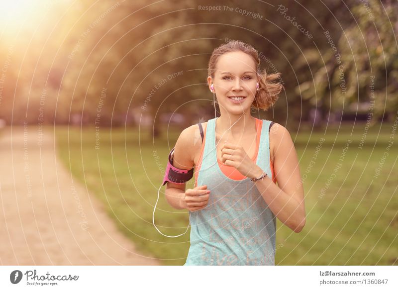 Recht athletische Frau, die in einen Park läuft Lifestyle Glück Sommer Musik Sport Joggen Erwachsene Landschaft Herbst Blatt Straße Bewegung Fitness hören