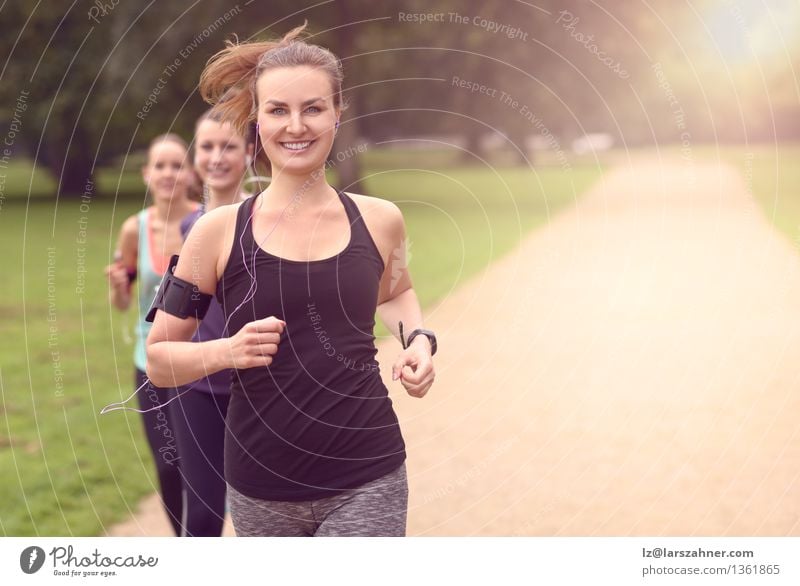 Athletische hübsche junge rüttelnde Frauen Lifestyle Erholung Sommer Musik Sport Joggen Telefon PDA Erwachsene Freundschaft Arme Menschengruppe Band Park