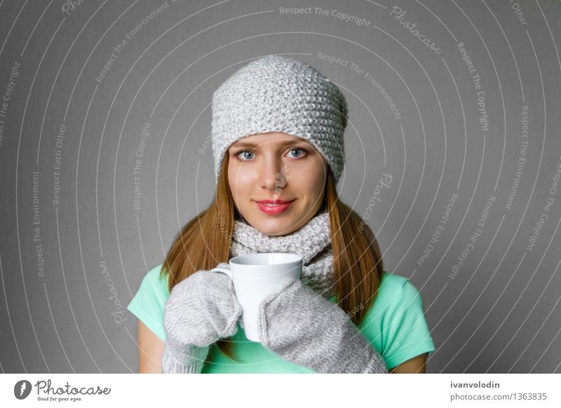 Lächelndes junges Mädchen in der Winterkappe, -schal und -handschuhe mit Becher Freude Glück schön Haut Gesicht Kosmetik Mensch Frau Erwachsene Wärme Mode