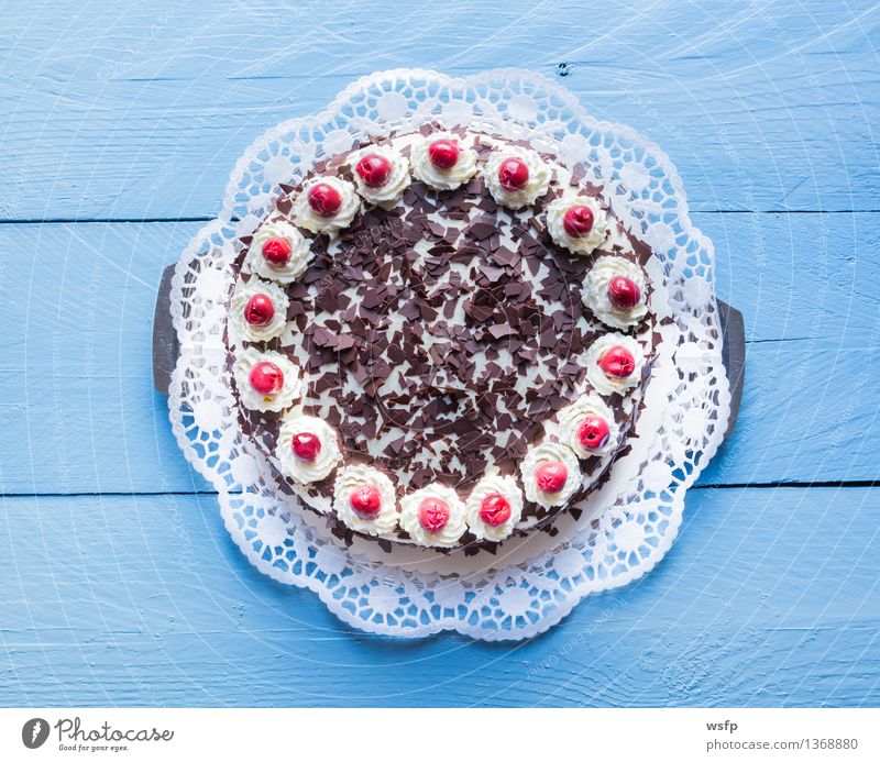 Schwarzwälder Kirschtorte auf blauem Holz Kuchen Dessert Torte Sahnetorte Kirsche Schaumgebäck Tortenspitze Backwaren Biskuit Holztisch rustikal