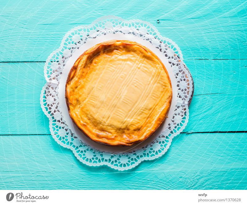 Käsekuchen auf türkisem Holz mit Tortenspitze Kuchen Dessert Quarkkuchen Quarktorte Backwaren Biskuit süßes Holztisch Landhaus rustikal Vogelperspektive