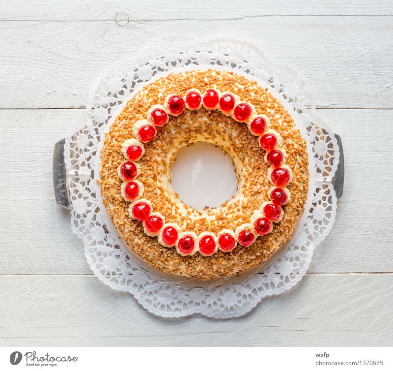 Frankfurter Kranz mit Kirschen auf weißem Holz Kuchen Dessert Buttercremetorte ringförmig kranzförmig Schaumgebäck Sahne Torte Tortenspitze Backwaren Biskuit