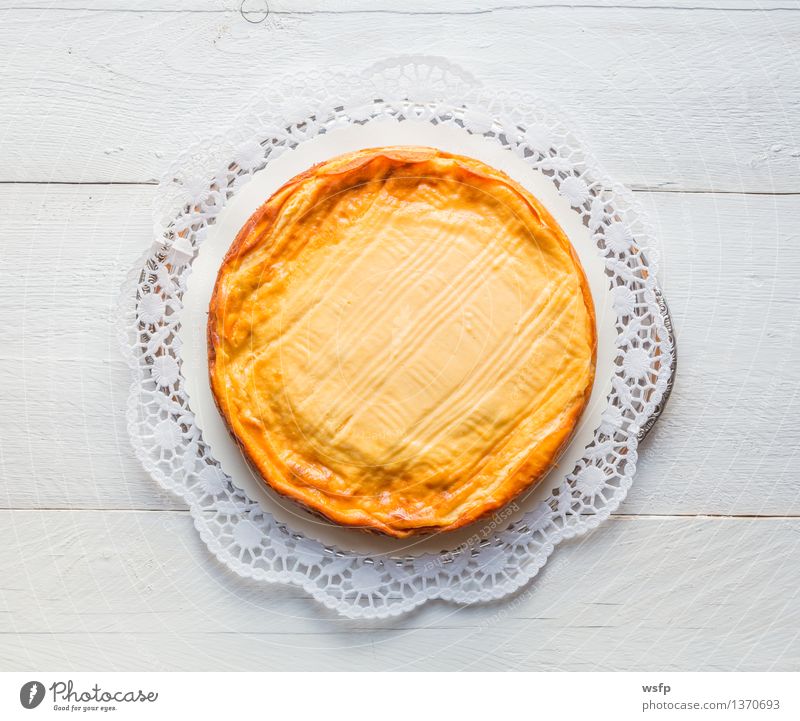 Käsekuchen auf weißem Holz mit Tortenspitze Kuchen Dessert Quarkkuchen Quarktorte Backwaren Biskuit Holztisch rustikal Vogelperspektive Süßwaren rund lecker