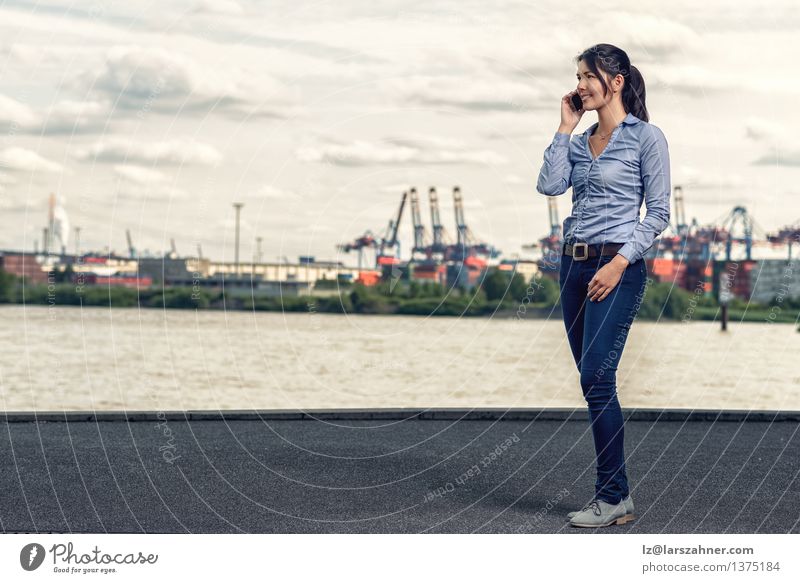 Frau, die dünne Jeans bei der Unterhaltung am Telefon trägt Sonne Business sprechen Erwachsene Hafen Jeanshose brünett Sonnenuntergang attraktiv lässig