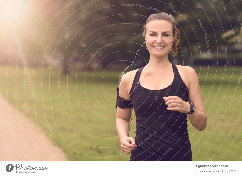 Hübsche Frau, die am Park mit Kopfhörern rüttelt Lifestyle Glück Sommer Musik Sport Joggen Erwachsene Landschaft Herbst Blatt Straße Bewegung Fitness hören