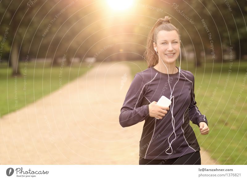 Hübsche Frau, die am Park mit Kopfhörern rüttelt Lifestyle Glück Sommer Musik Sport Joggen Erwachsene Landschaft Herbst Blatt Straße Bewegung Fitness hören