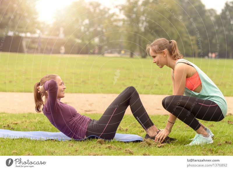 Die athletische Frau, die Locke tut, trainiert oben Lifestyle Glück Körper Sport Fitness Sport-Training Sportler Erwachsene Freundschaft Arme Fuß Gras Park